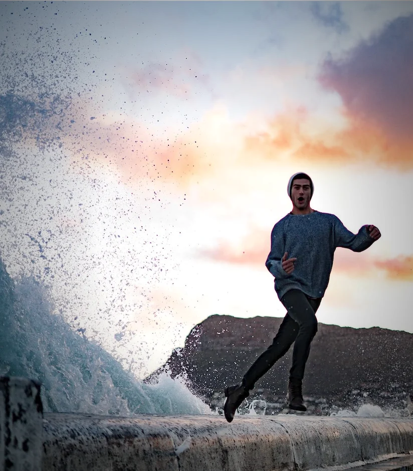 Zandré leaping the sea wall as a wave breaks at sunset